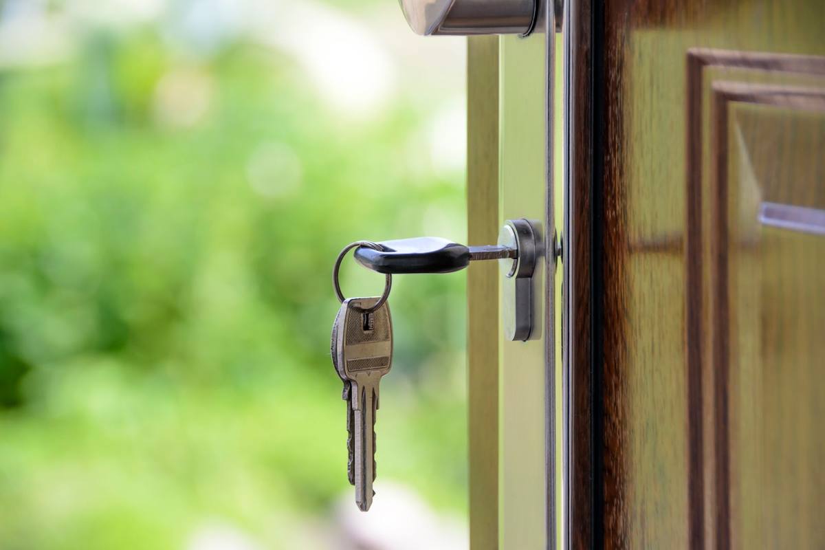 Hand placing a key into the lock of a front door to secure a vacant property